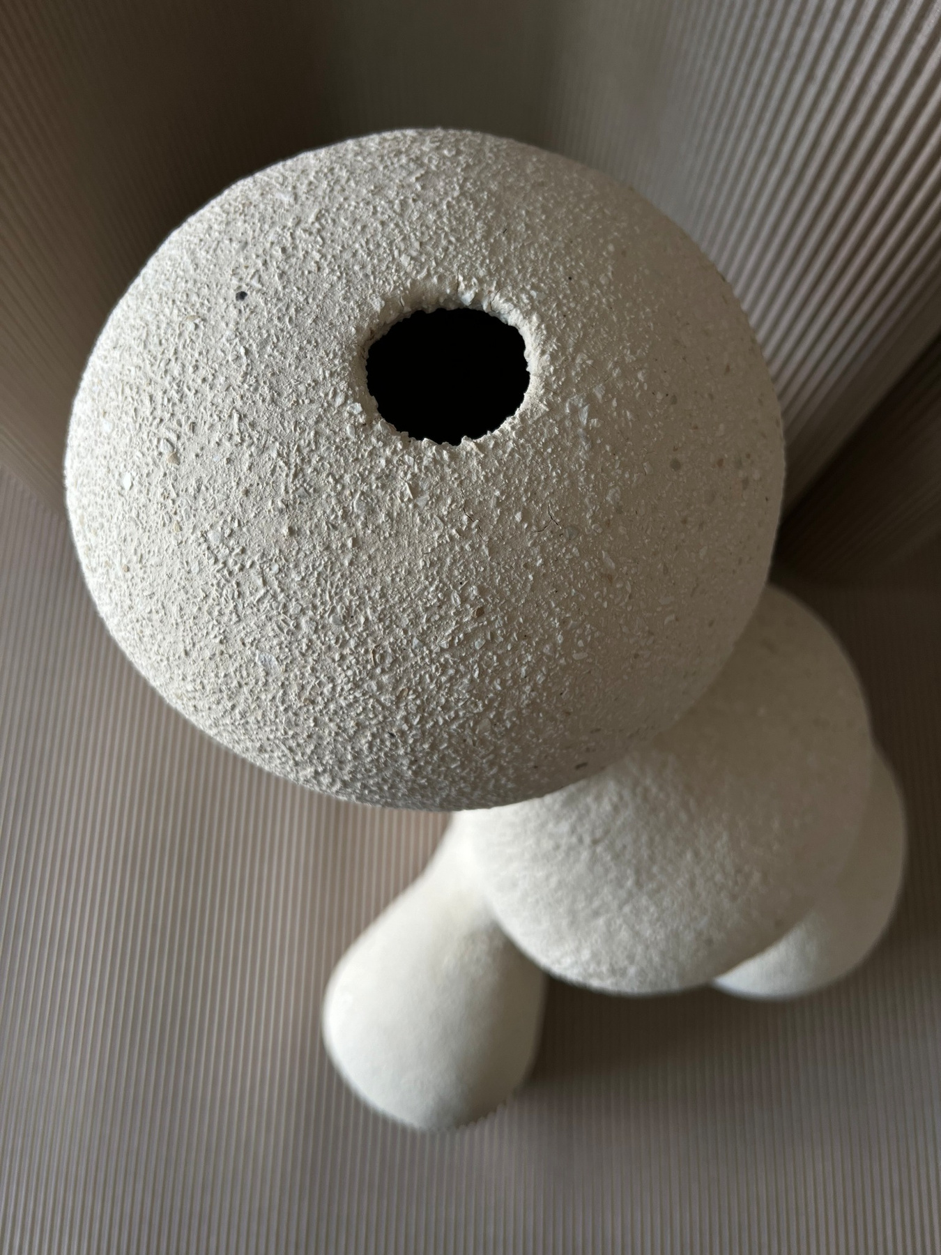 bialy-ceramiczny-wazon-organiczny-detal-otworu-04 Widok z góry na biały ceramiczny wazon o kulistej górnej części, niewielkim otworze i płynnych organicznych formach