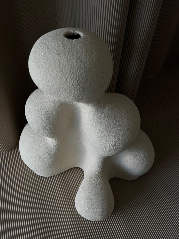 bialy-ceramiczny-wazon-organiczny-perspektywa-06 Biały ceramiczny wazon artystyczny pokazany pod kątem, z połączonymi organicznymi bryłami i niewielkim otworem u góry