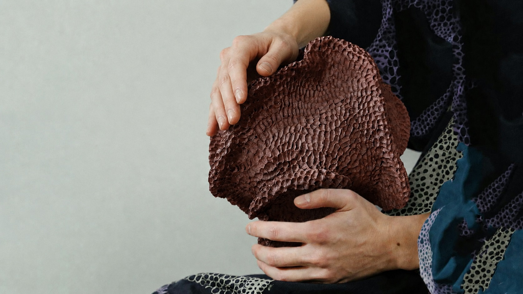 a dark burgundy sculptural ceramic vase with an organic, highly textured surface